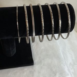 Thin metal bangle bracelets. Set of seven. Each carved with a different design.